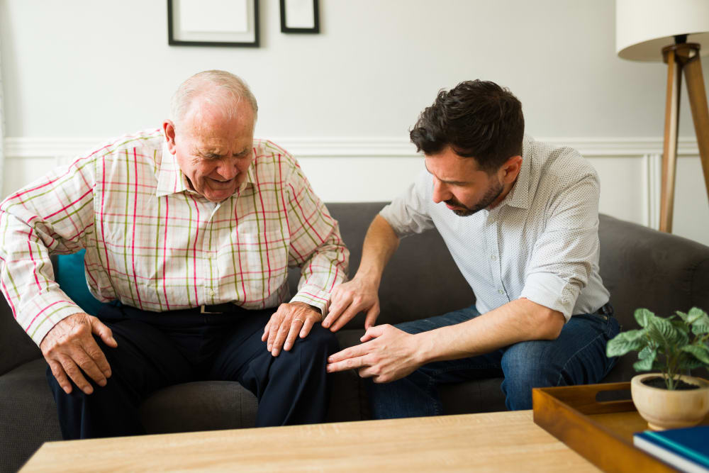 Son checking the knee pain of his sick elderly father